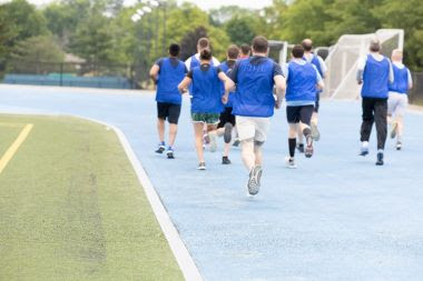 People wearing blue vests running on a blue track