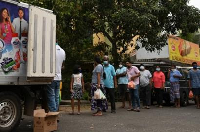 People line up to buy milk from a vendor along a street during a government-imposed nationwide lockdown as a preventive measure against the COVID-19 coronavirus in Colombo on March 30, 2020.