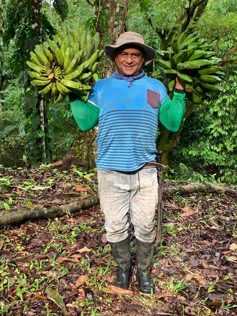 A man stands with two bundles of bananas in his hands