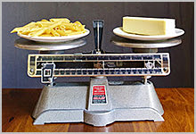 A balance scale with pasta/carbs weighed against butter/fat.
