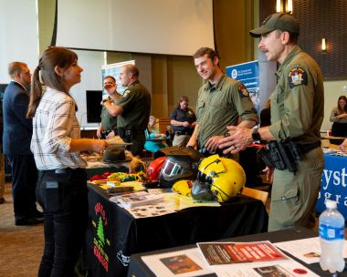 two rangers at an informational table speak to a student at a career fair
