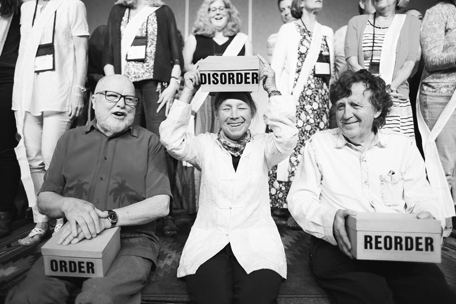 Image of core faculty at the Living School symposium holding boxs that read "order" "disorder" and "reorder"