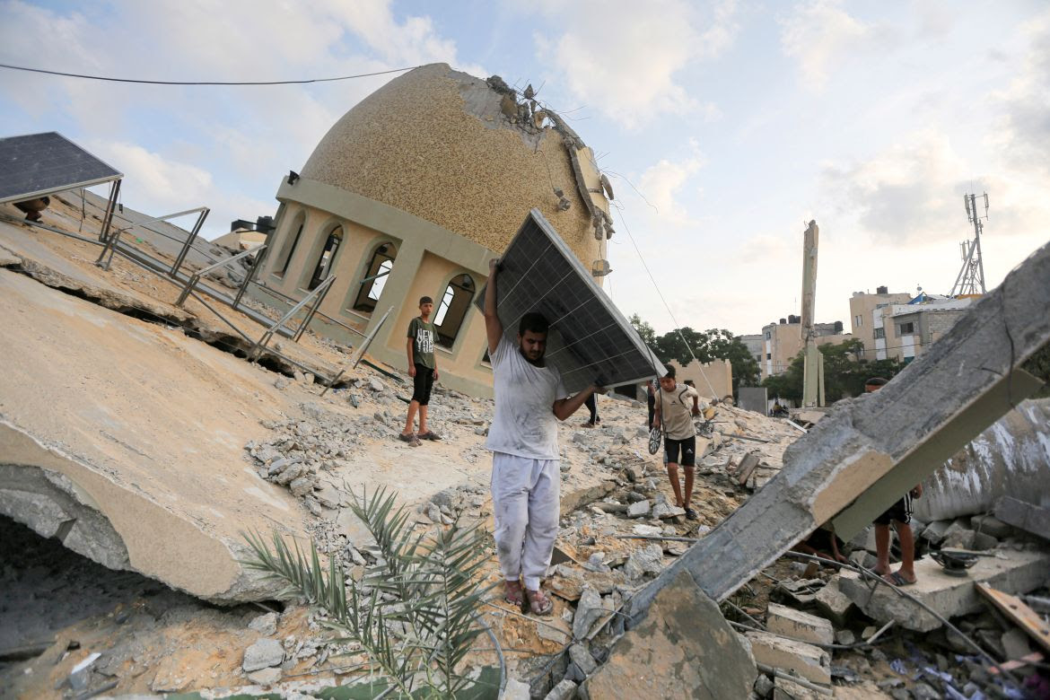 A man takes a solar panel from a mosque destroyed in an Israeli air strike in Khan Younis