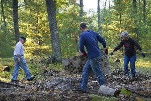 Two men and a woman clean up dumped trash and debris from state forest land in Grand Traverse County, Michigan