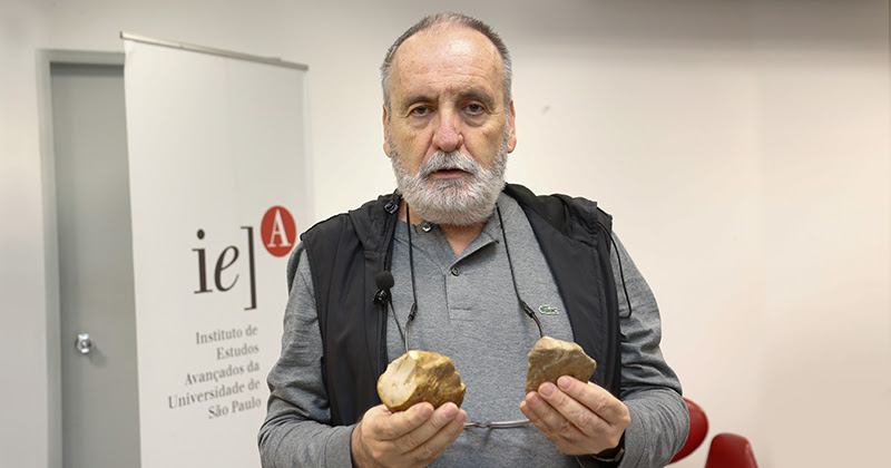Professor Walter Neves mostra antigos artefatos de pedra lascada em suas mãos