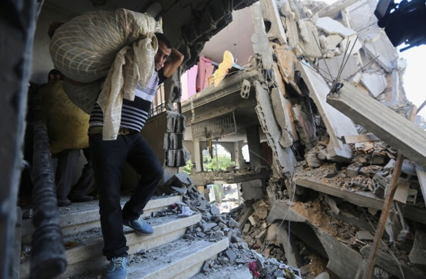 Palestinians carry belongings in a house after it was hit by an Israeli missile strike in Gaza City.