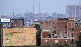 This picture taken on August 31, 2022 shows a construction billboard announcing the site of new alternative accommodation residential towers as part of the government development plans of the slums of the Nile island of Warraq, opposite Cairo's northern shore.