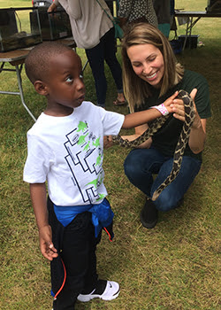 young boy touching fox snake held by DNR staffer