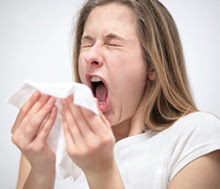 Woman sneezing into a tissue.