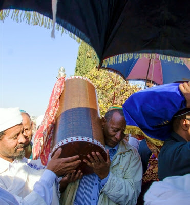 An Ethiopian Jewish man and a Kes, a
                          religious leader of the Ethiopian Jews, carry
                          the Torah.