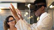 A man wearing a virtual reality headset stares at his hands.