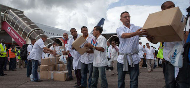 Los primeros miembros de un equipo de 165 médicos cubanos y trabajadores de la salud descargan ellos mismos las cajas de medicamentos y material médico de un avión.