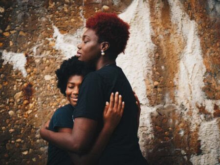 Black woman hugging black teenager.