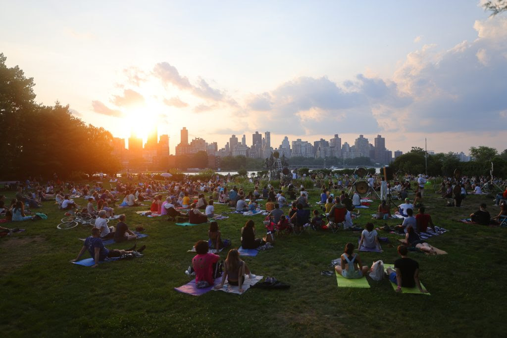 Sunset at Socrates with a few clouds, looking at the skyline and East River, filled with picnickers