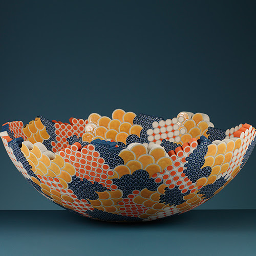 A photograph of a colourful ceramics bowl by Frances Priest on a blue background.