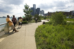 Visitors take in the sights along the Detroit Riverfront, the Renaissance Center in the background