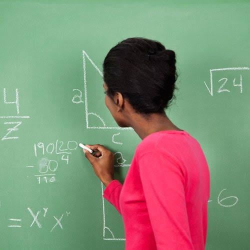 A woman writing math equations on a chalk board