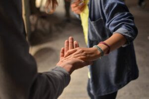 Two people holding hands, reaching out for support