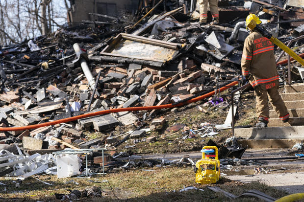 A partially melted child's toy is seen as firefighters work the scene after an explosion 