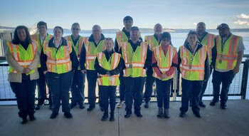 13 people posing for a photo at a ferry terminal