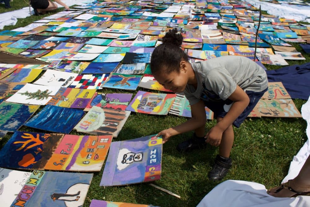 A young child examines every tile before placing them inside the whale mosaic on Boston Common. (Miriam Wasser/WBUR)