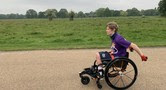 Image of a boy using his wheelchair to move through a park