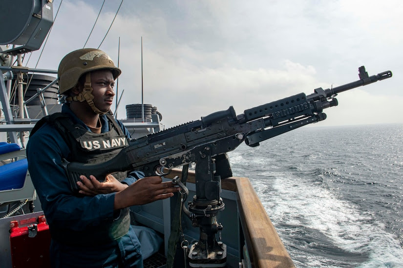 A sailor mans a military weapon while aboard a ship.