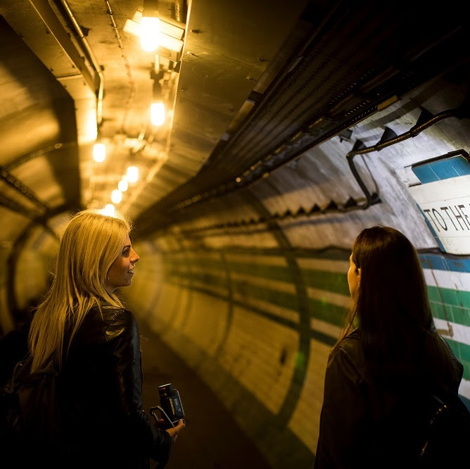 Two people chatting in a tunnel with tiled walls