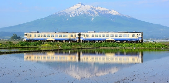 The background is Mt.Iwaki, and the two-cars train of Gono Line runs in the countryside, Aomori, Japan.