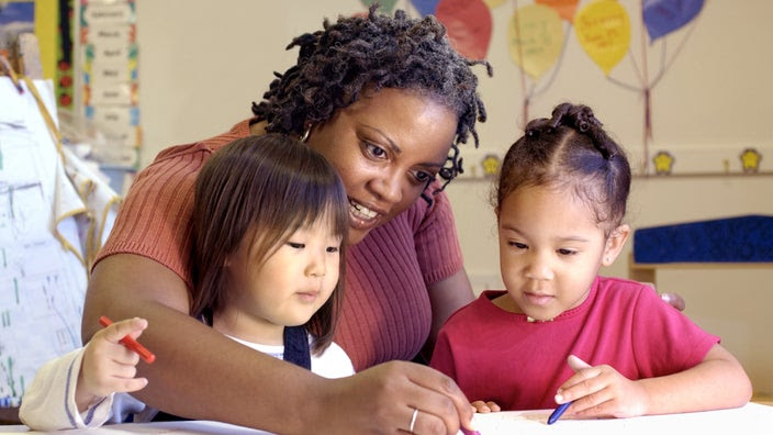 Teacher working with young students on an art project.