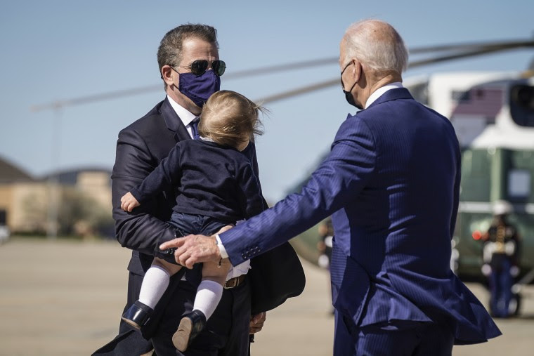 President Joe Biden talks with his son Hunter Biden as he holds his grandson Beau Biden as they walk to board Air Force One at Andrews Air Force Base, Md., on March 26, 2021.