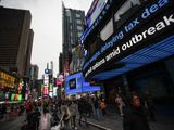 Pedestrians pass under a news ticker in Times Square, Wednesday, March 11, 2020, in New York, N.Y. The number of coronavirus cases in New York state jumped Sunday to more than 100, a spread that forced the suspension of classes at schools across the state, including a district that has a faculty member with a positive test and Columbia and Hofstra universities. For most people, the new coronavirus causes only mild or moderate symptoms. For some it can cause more severe illness. (AP Photo/John Minchillo)