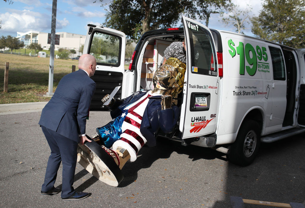 Weird photo of Biden stuffing large clown sculpture into rental van.