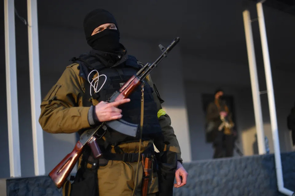 Armed civilian volunteers stand alert on a street in Kyiv.