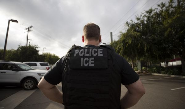 In this July 8, 2019, photo, a U.S. Immigration and Customs Enforcement (ICE) officer looks on during an operation in Escondido, Calif. A federal judge has prohibited U.S. immigration authorities from relying on databases deemed faulty to ask law enforcement agencies to hold people in custody, a setback for the Trump administration that threatens to hamper how it carries out arrests. (AP Photo/Gregory Bull) **FILE**