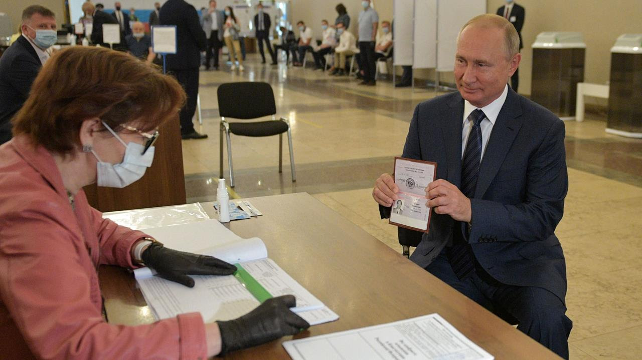 Russian President Vladimir Putin shows his passport to a member of a local electoral commission at a polling station on the last day of a weeklong nationwide vote on constitutional reforms in Moscow, Russia July 1, 2020.