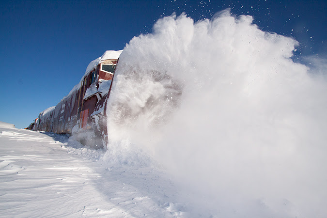 An engine plowing through a mound of snow