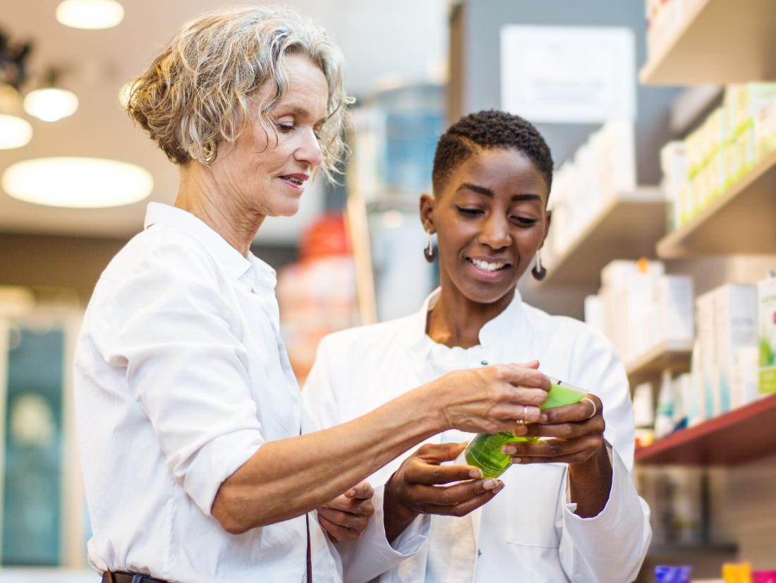 a pharmacist helping a female customer choose a produce.