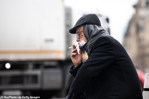 It comes after a study found 4.4% of 350 coronavirus patients hospitalized were regular smokers and 5.3% of 130 patients at home smoked compared to the general population. Pictured: A man wearing a face mask smokes a cigarette in Paris, France, March 16