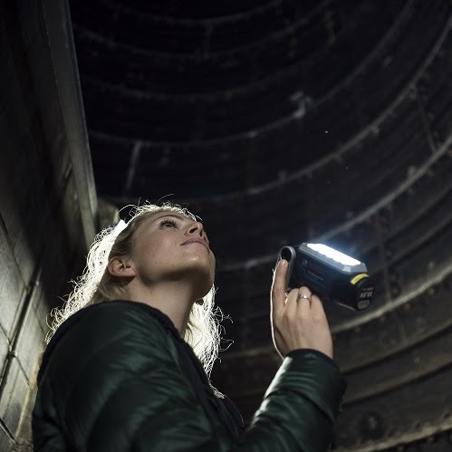 A person shining a torch up a large air vent shaft