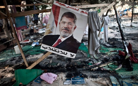 A photo taken on Aug 15, 2013 shows a portait of Mohamed Morsi, by then Egypt's ousted president, hanging admist debris at Rabaa al-Adawiya square in Cairo