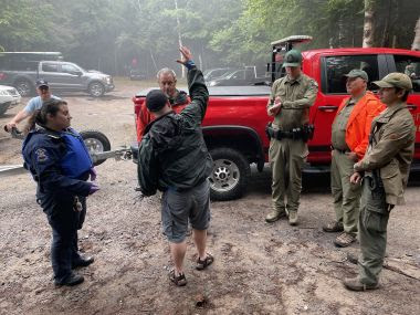 Rangers gather around person explaining what happened with a lightning strike at campground