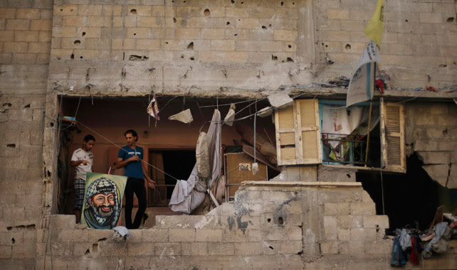 Palestinos, con un cuadro de Arafat, en su casa destruida por los bombardeos.