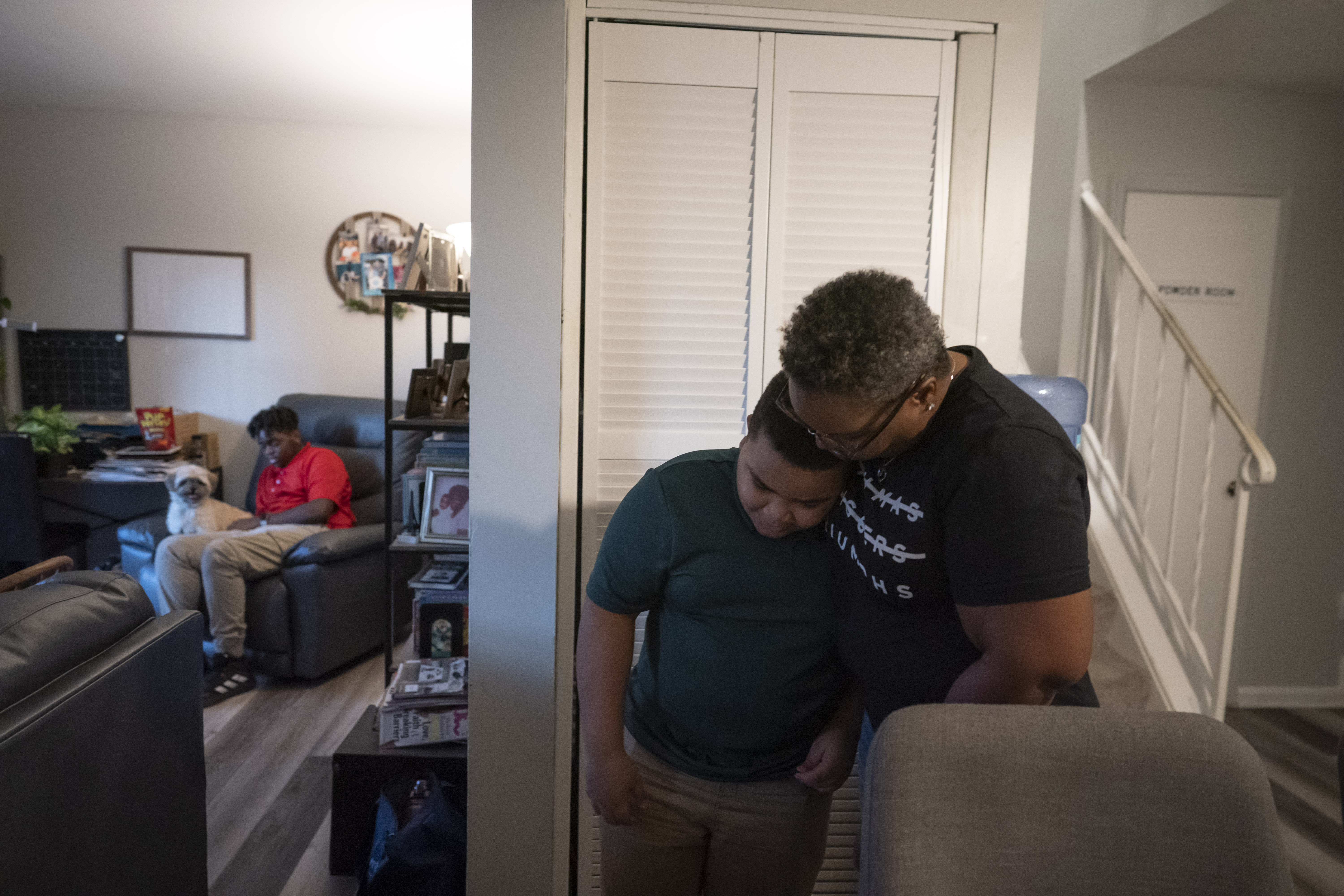 Melanese Marr-Thomas hugs her youngest child, Savion Thomas, while her other son, Zachary Marr, shares a seat with their pet dog, Ryder, in their living room in District Heights, Md., on Wednesday, Sept. 21, 2022. 
