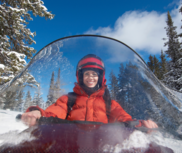 A female snowmobiler smiles at the camera. 