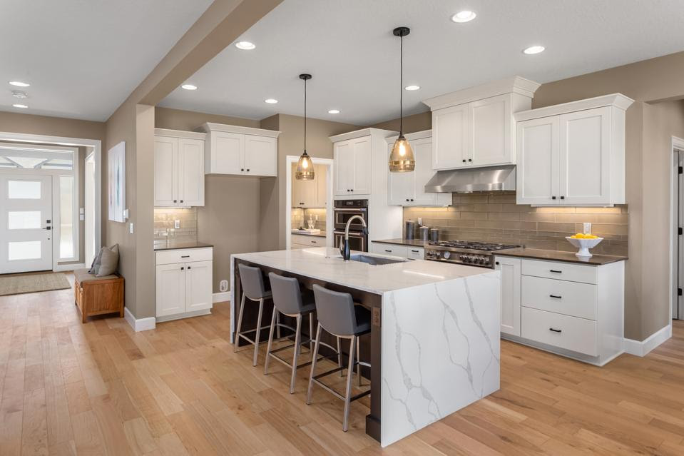 beautiful kitchen in new home with island, pendant lights, and hardwood floors.