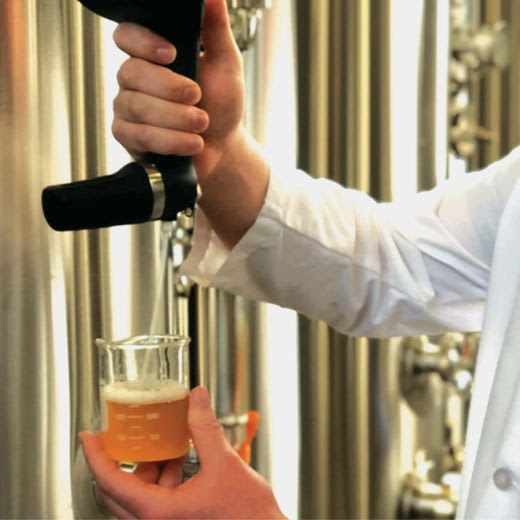 person pulling draft of beer into a beaker