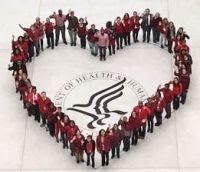 image from high above of several dozen people wearing red forming the shape of a heart around the HHS seal