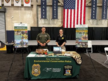 ECO and Investigator stand at informational table during career fair