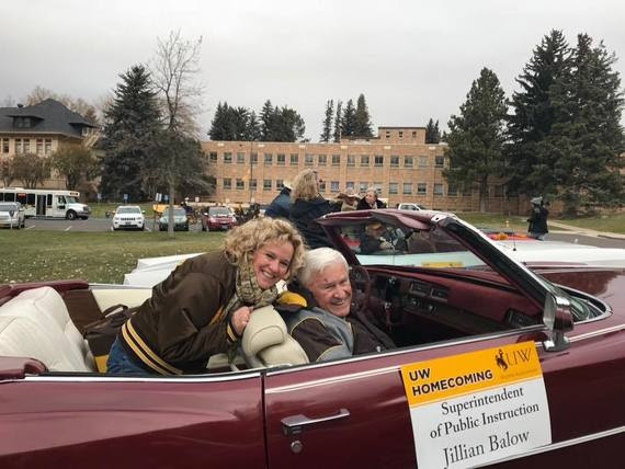 Superintendent Balow sits in the backseat of a red convertible with her dad in the front seat for the University of Wyoming's homecoming parade in Laramie. A sign on the car reads, "UW Homecoming, Superintendent of Public Instruction, Jillian Balow."